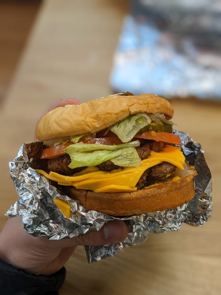 A Five Guys Cheeseburger with mayo, lettuce, pickles, tomatoes, grilled onions, grilled mushrooms, ketchup, mustard, relish and jalapenos. 